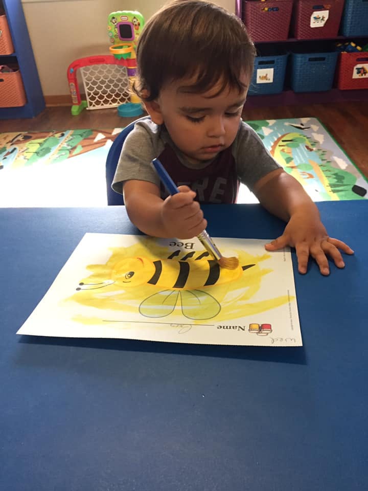 Child painting a bee on paper