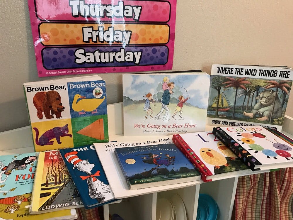 Children's books displayed on a shelf with a calendar above
