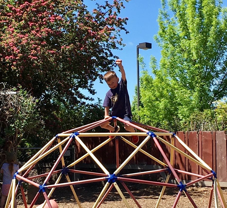 Child on top of a geometric dome climber