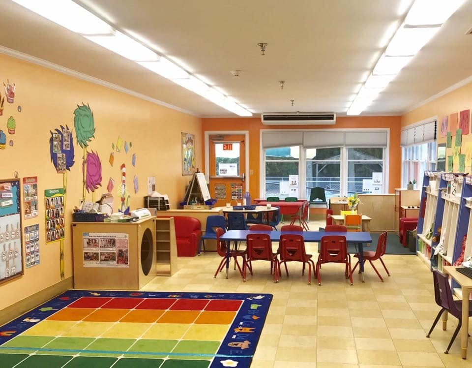Empty classroom with small tables and chairs, colorful rug