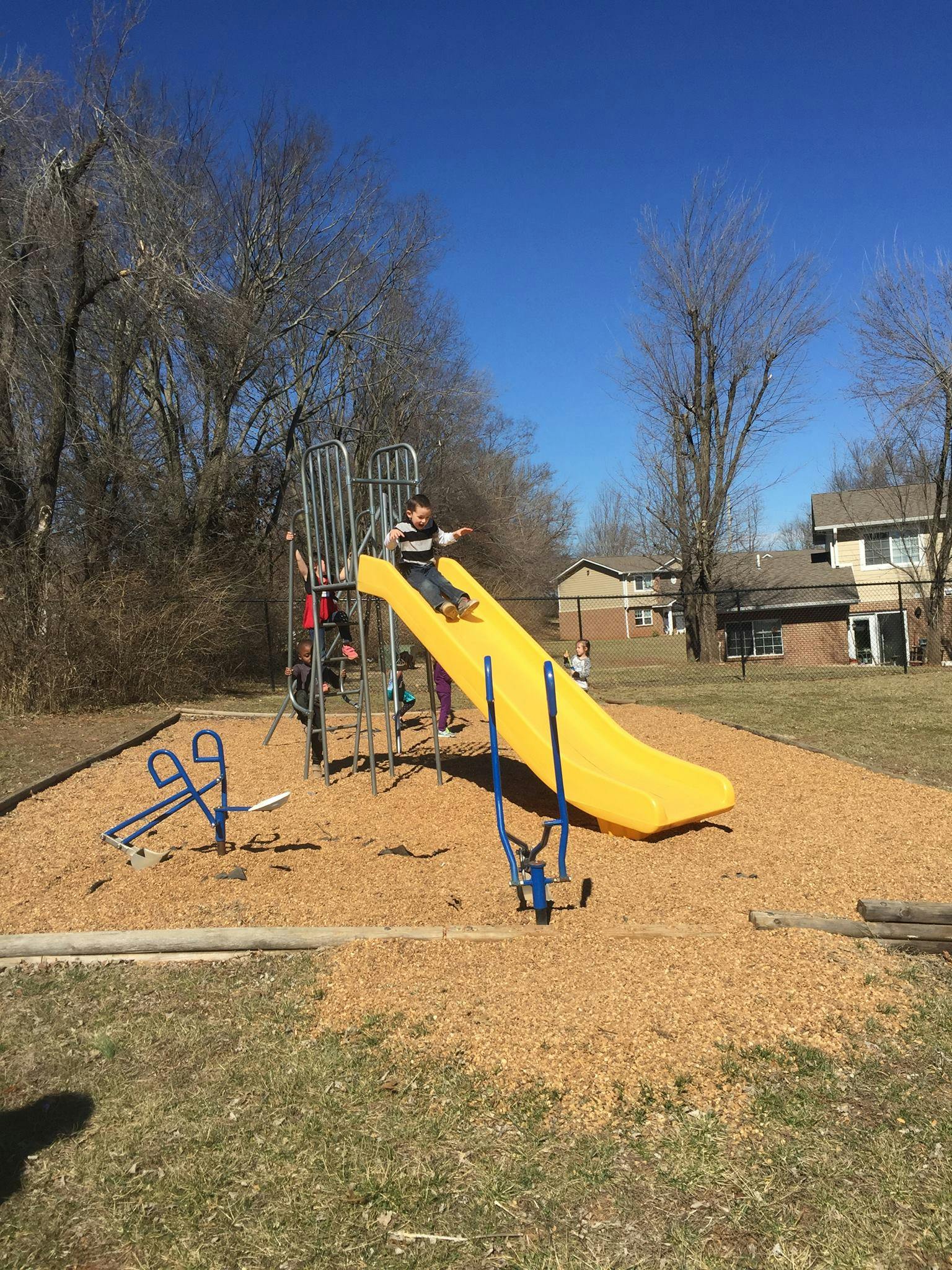 Child sliding down a yellow slide on a playground