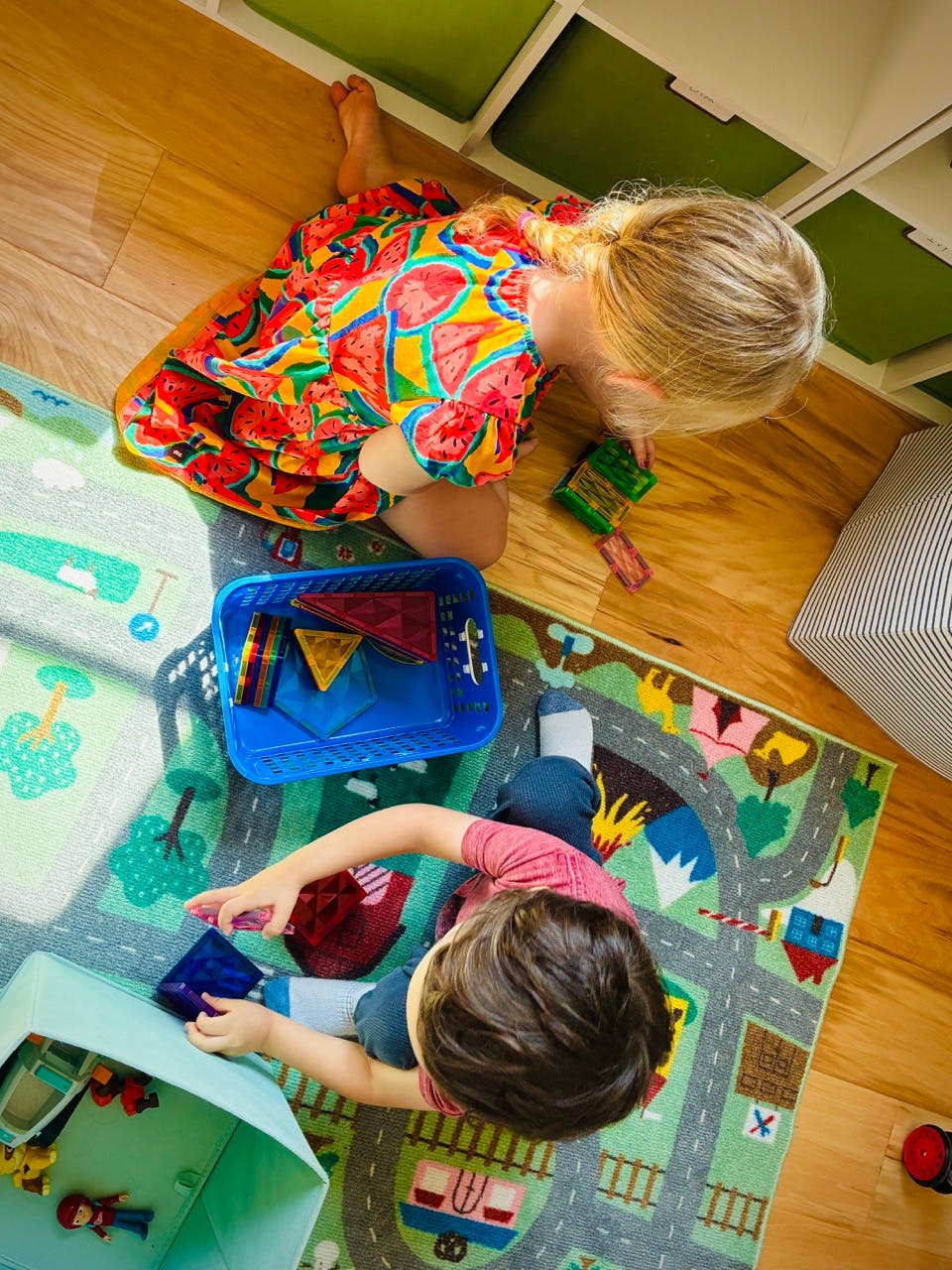 Two children playing with colorful magnetic tiles on a rug
