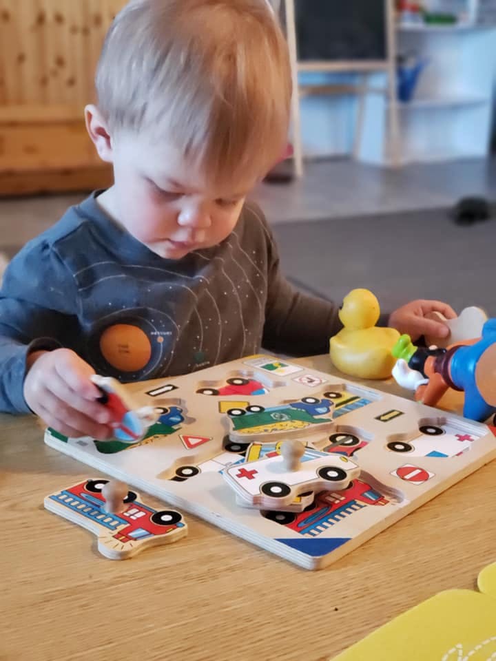 Child playing with a wooden vehicle puzzle