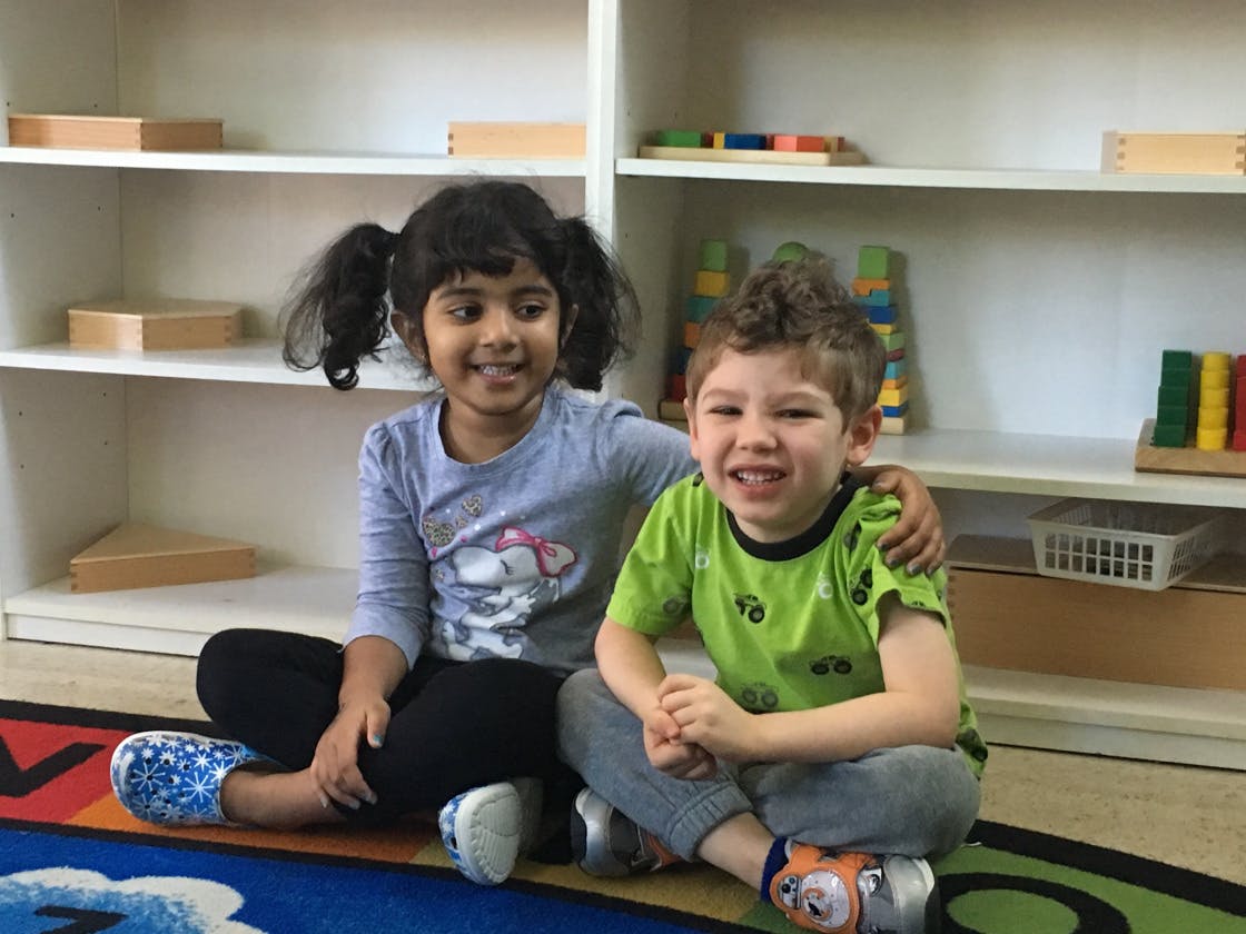 Two children sitting on a rug in a classroom