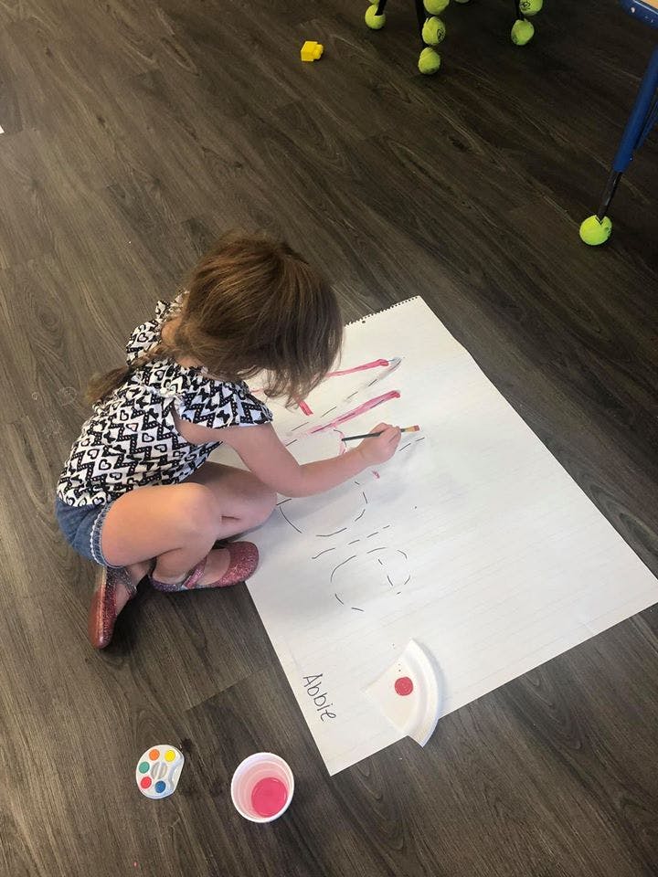 Child painting on a large sheet of paper on the floor