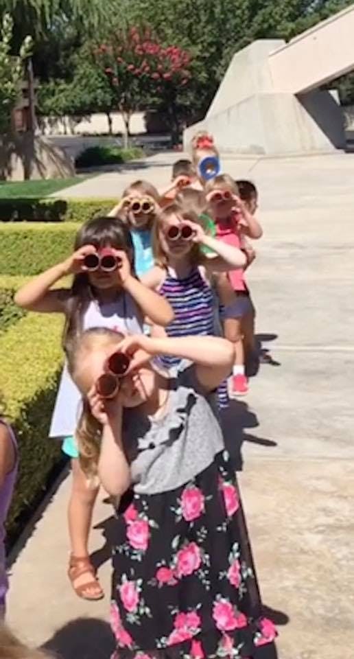 Children in a line looking through cardboard tubes