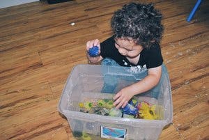 Child playing with toys in a clear plastic bin