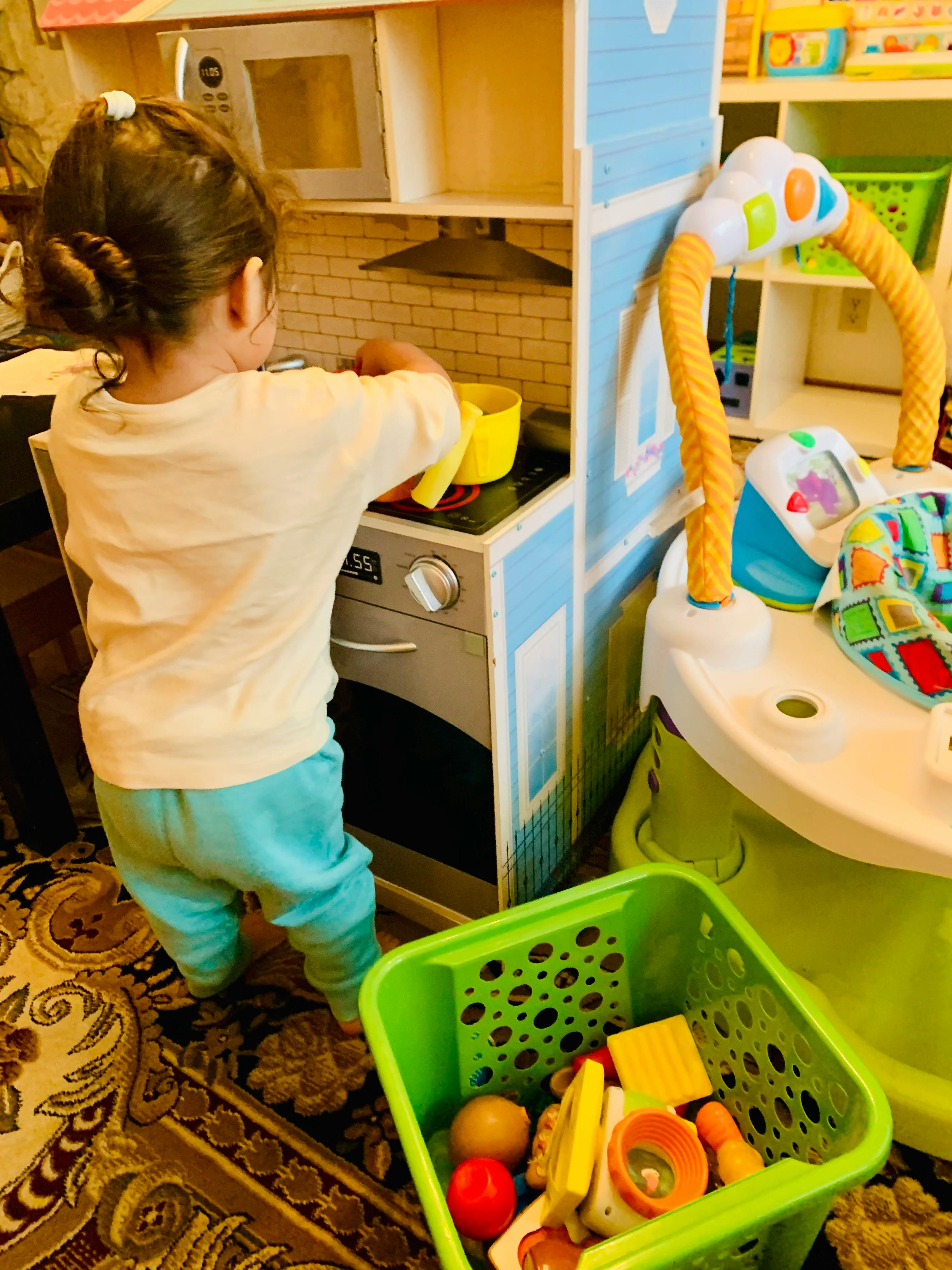 Child playing with a toy kitchen set