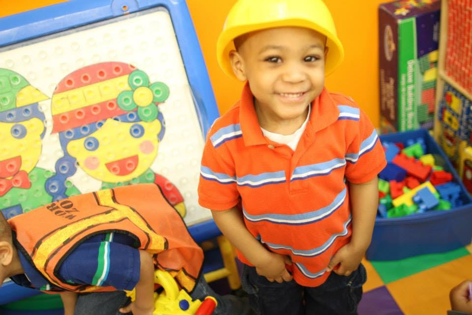 Child in a yellow hard hat and orange striped shirt