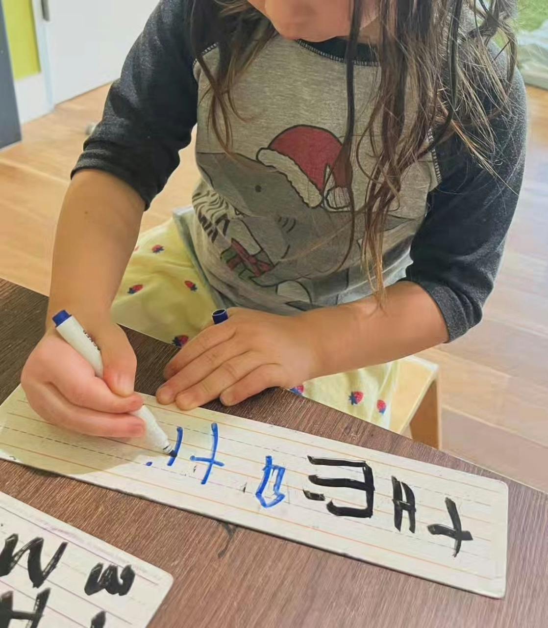 Child writing on a small whiteboard with a marker