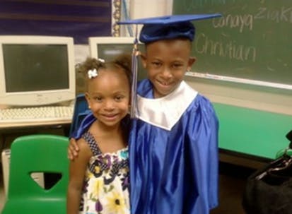 Child in graduation cap and gown with another child