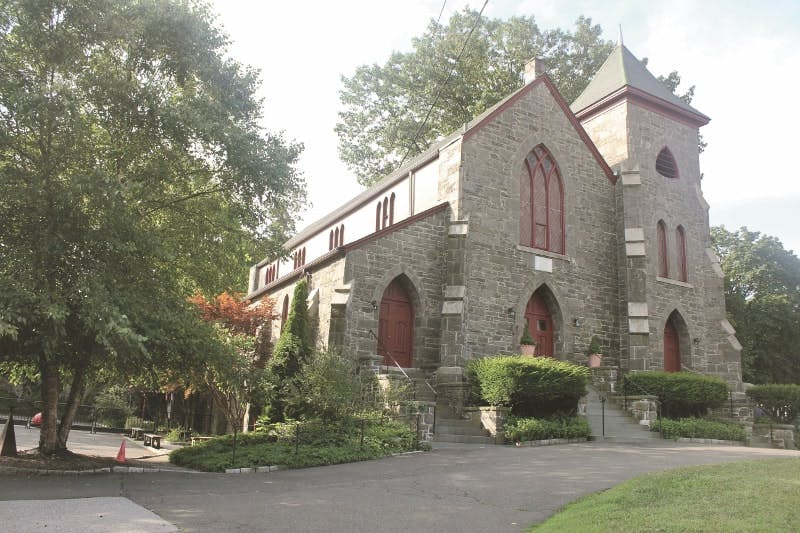 Stone church building with a tower and red arched doors