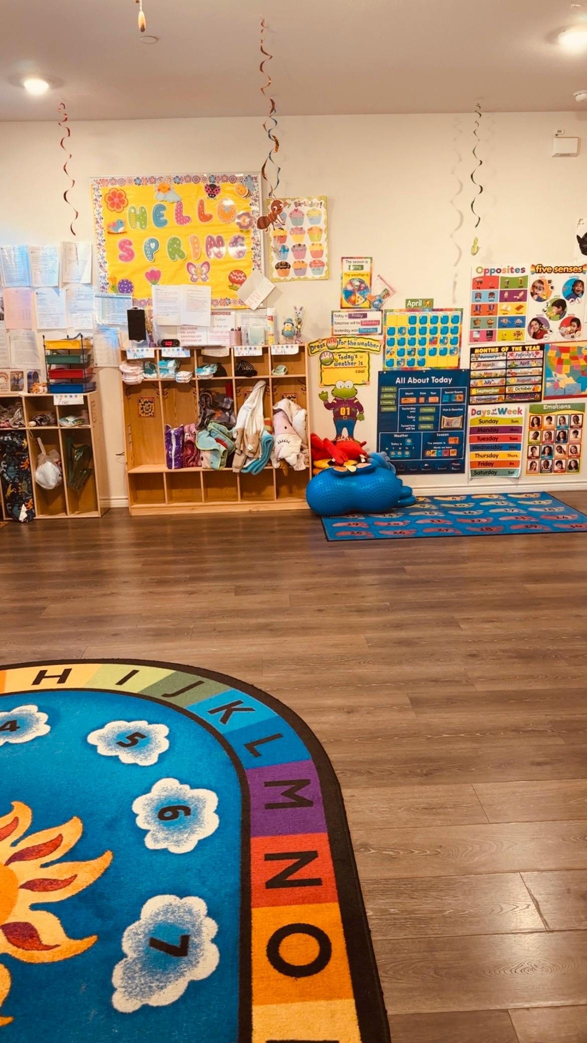 Classroom with a colorful rug, cubbies, and educational posters on the wall