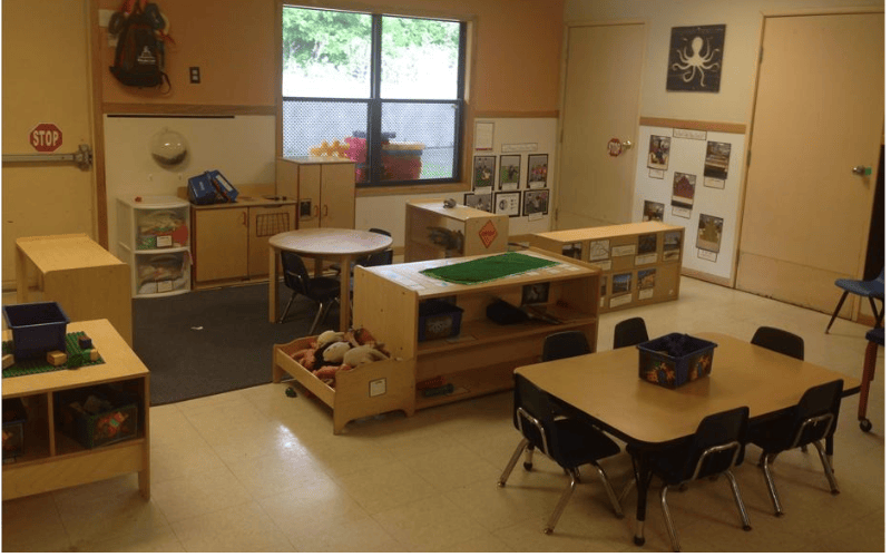 Classroom with tables, chairs, shelving units, and a large window