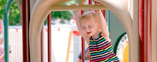 Child hanging from playground equipment
