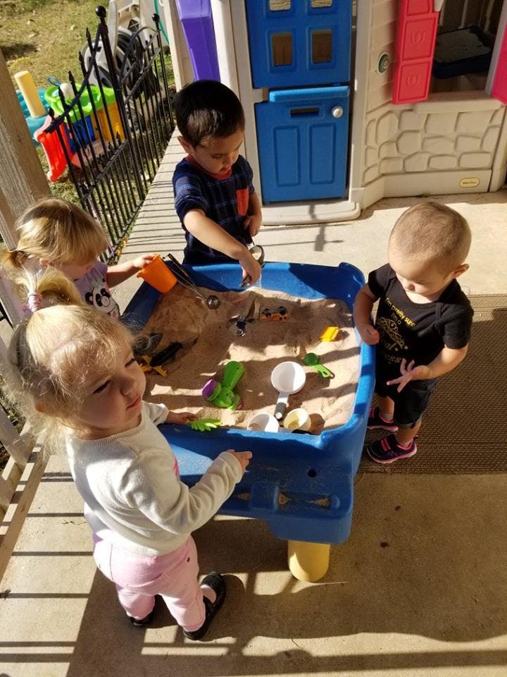 Children playing in a sand and water table outdoors