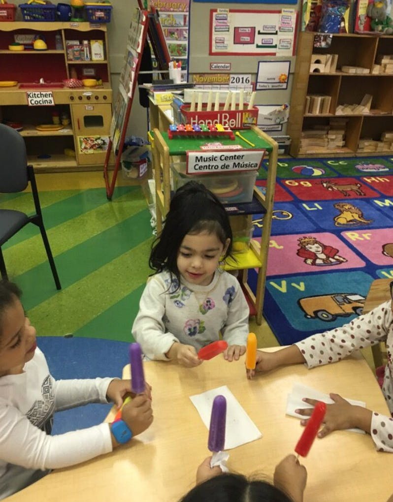 Children holding colorful popsicle-shaped objects at a table