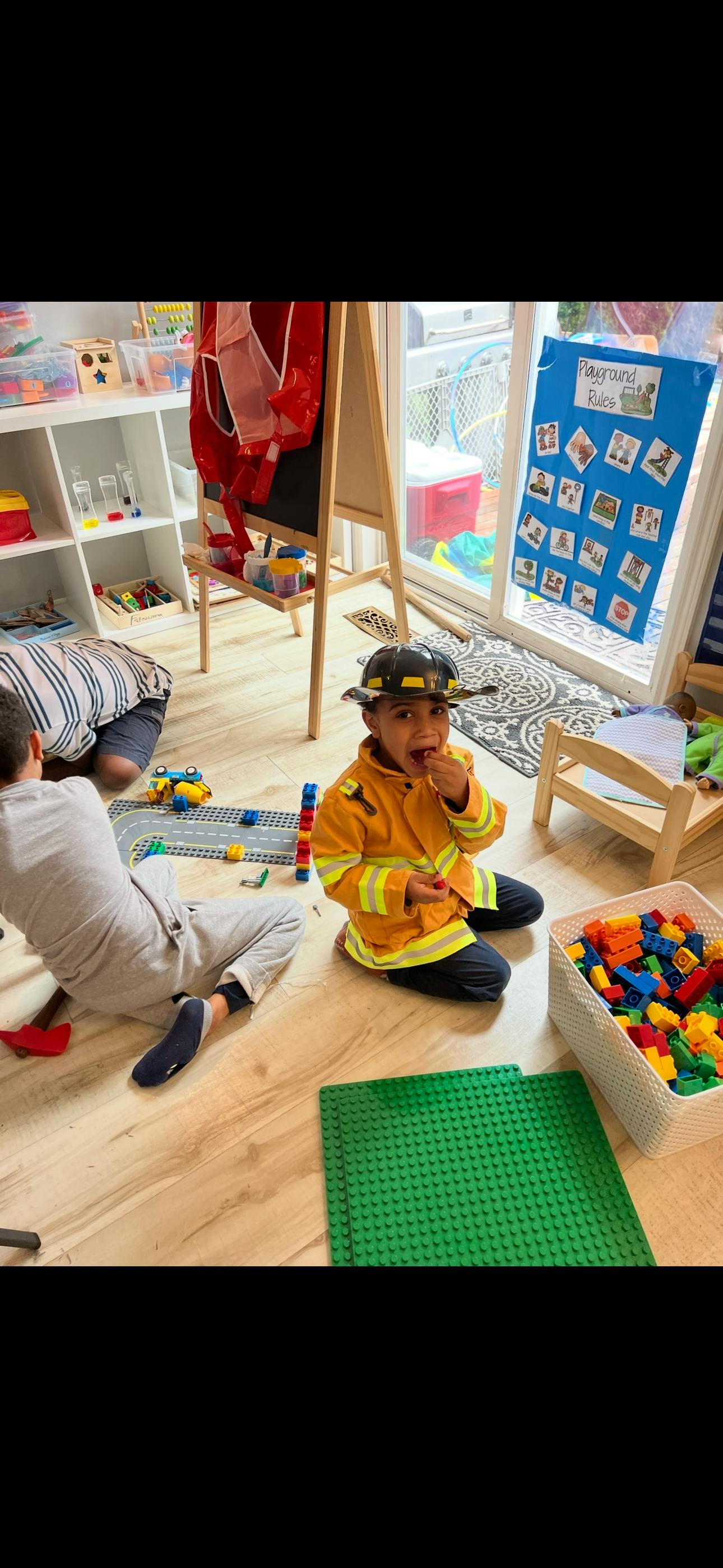 Child in firefighter costume playing with blocks on floor
