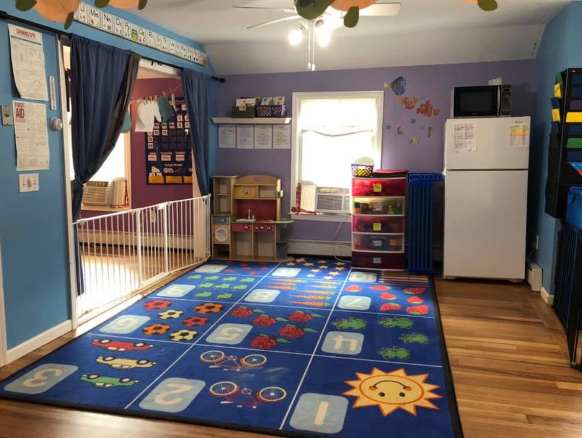 Playroom with a blue rug, white refrigerator, and window
