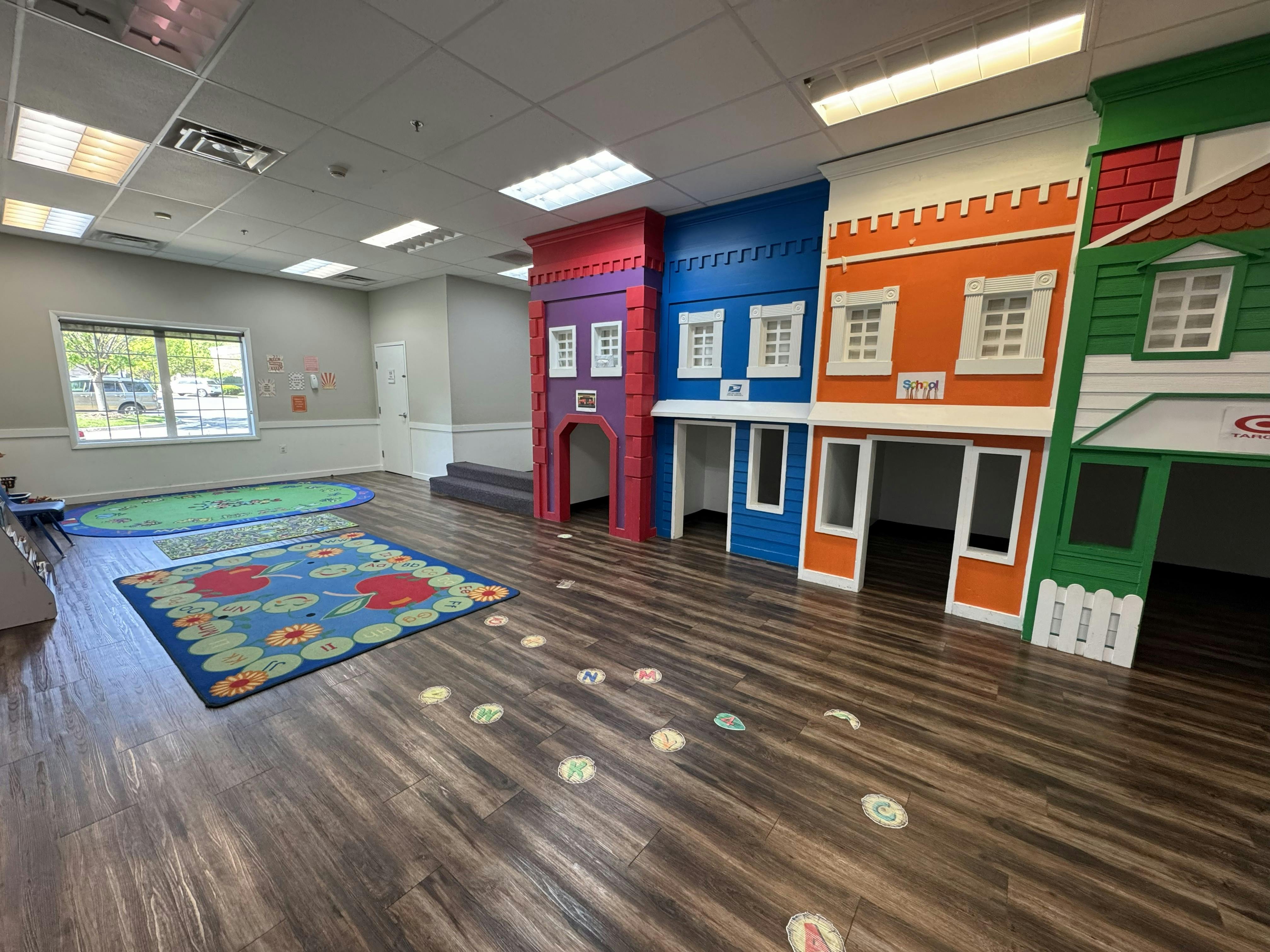 Playroom with colorful miniature house facades and alphabet floor decals