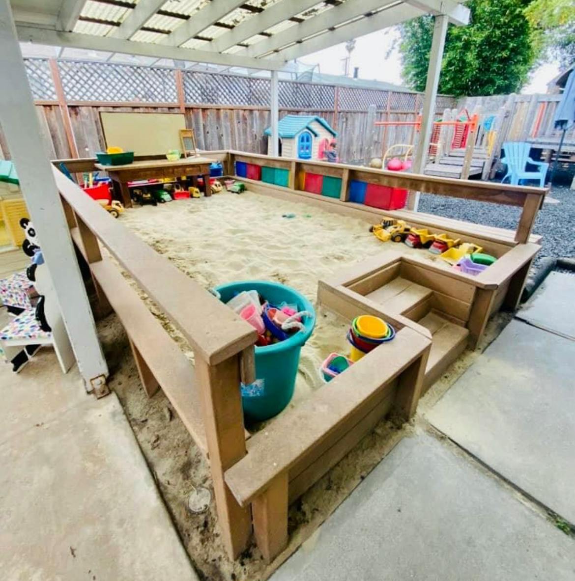Outdoor sandbox with toys and a blue bucket