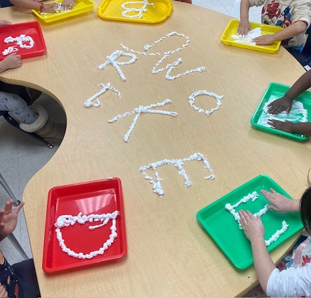 Children learning letters with shaving cream on a table