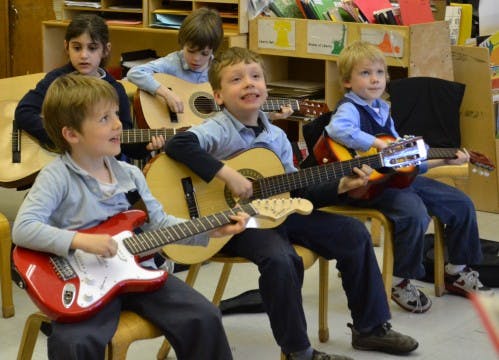 Children playing guitars in a classroom