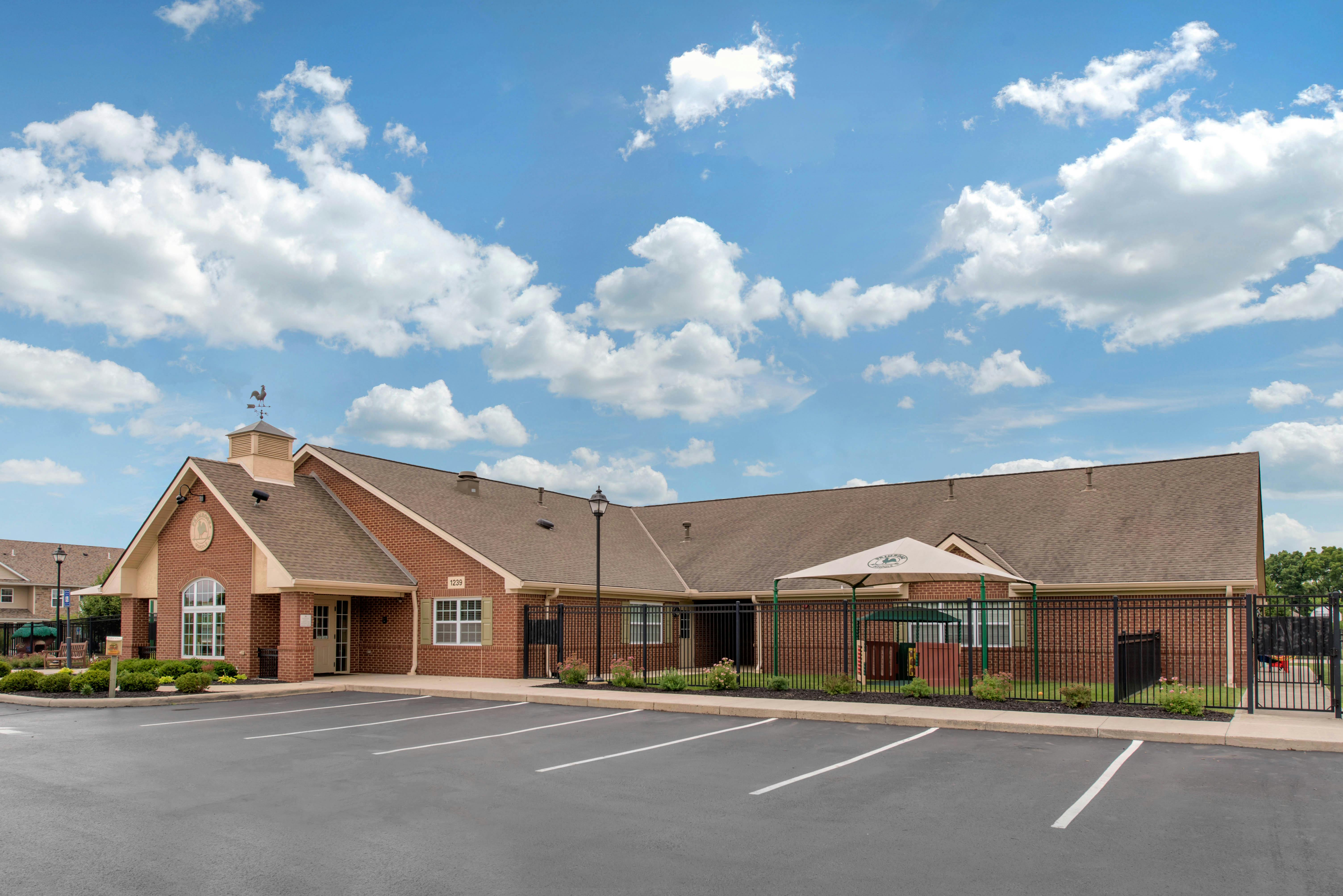 Brick building with a parking lot and fenced-in playground area
