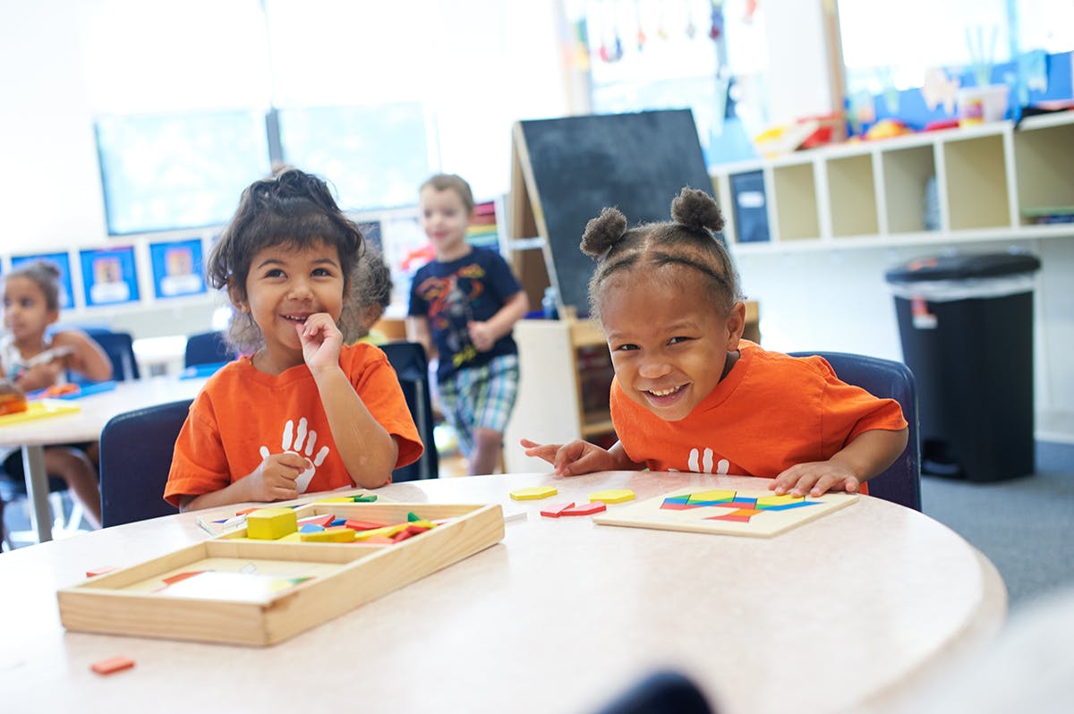 Two children at a table with puzzles in a classroom