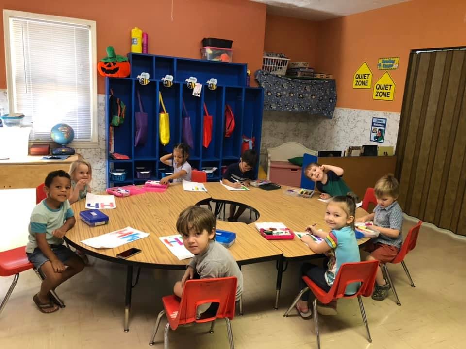 Children sitting around a large table in a classroom