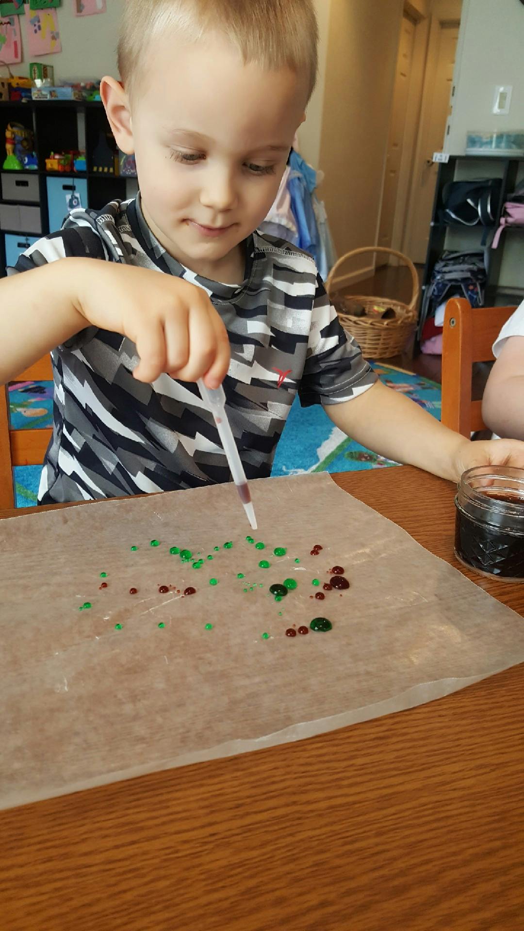 Child using a dropper to place colored liquid onto paper