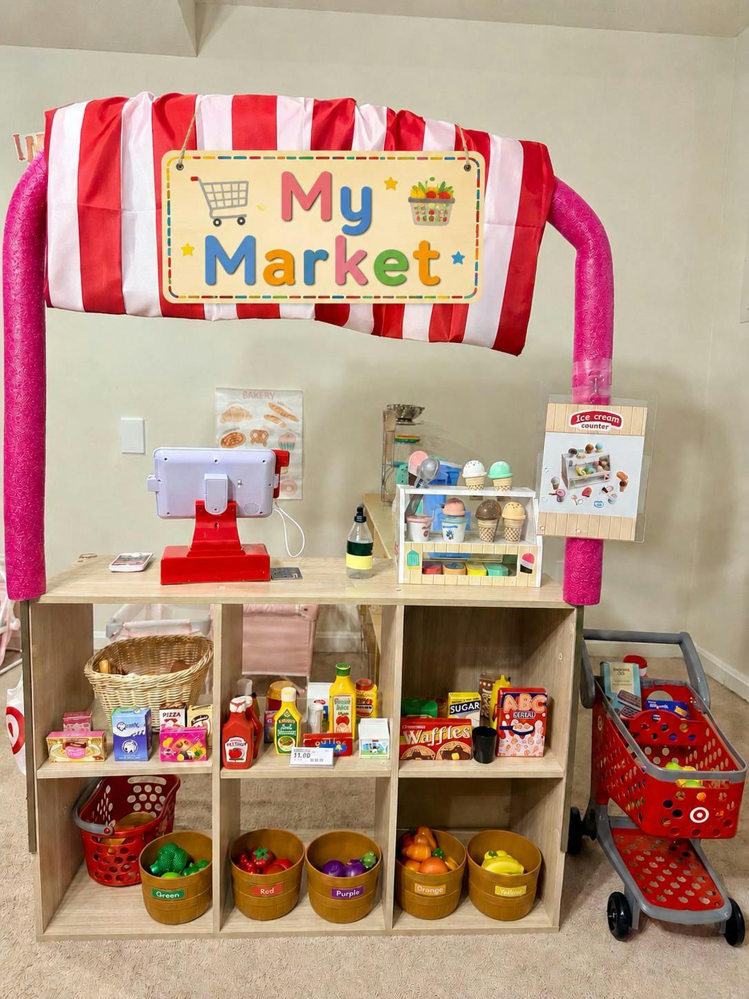 Child's play market with "My Market" sign, shelves of food, and a shopping cart