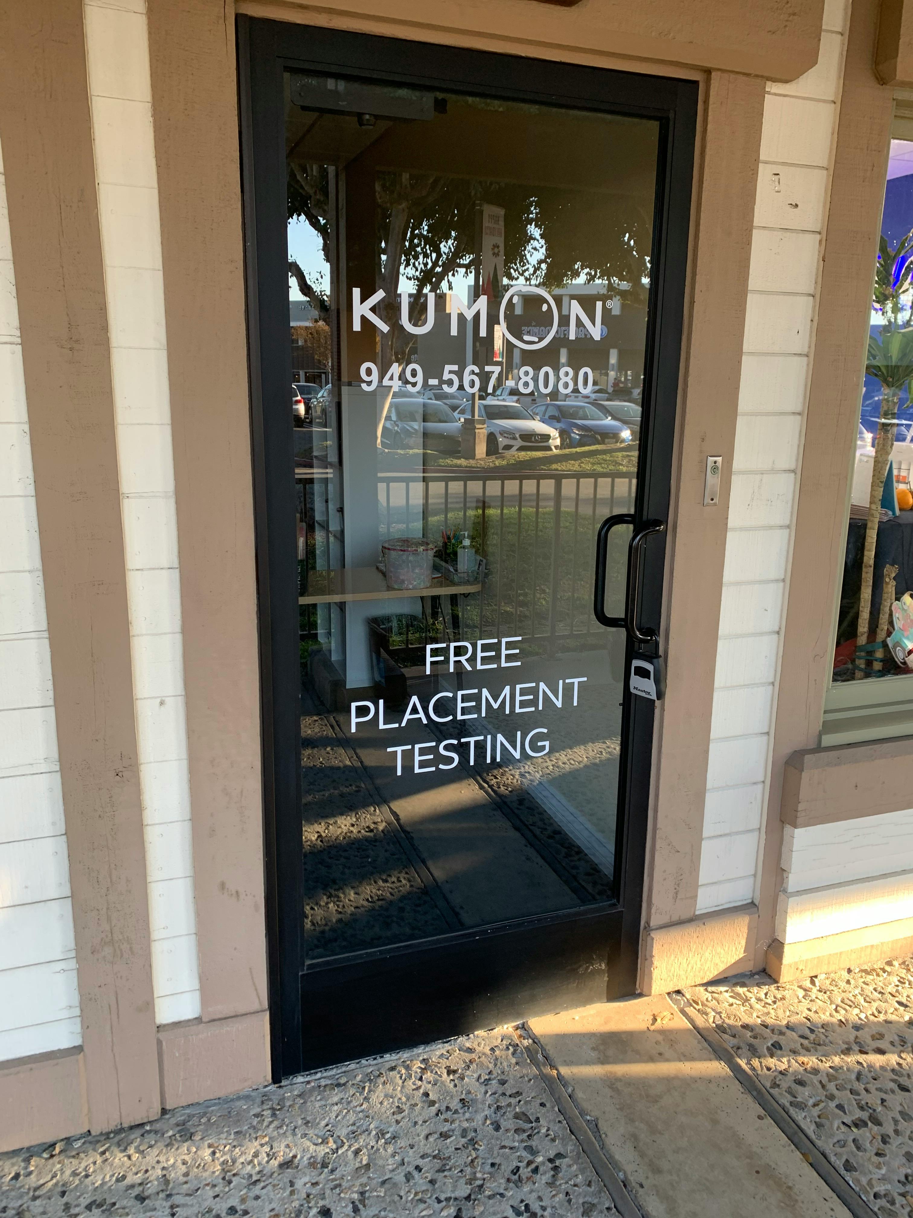 Glass door of a Kumon learning center with white text about free placement testing