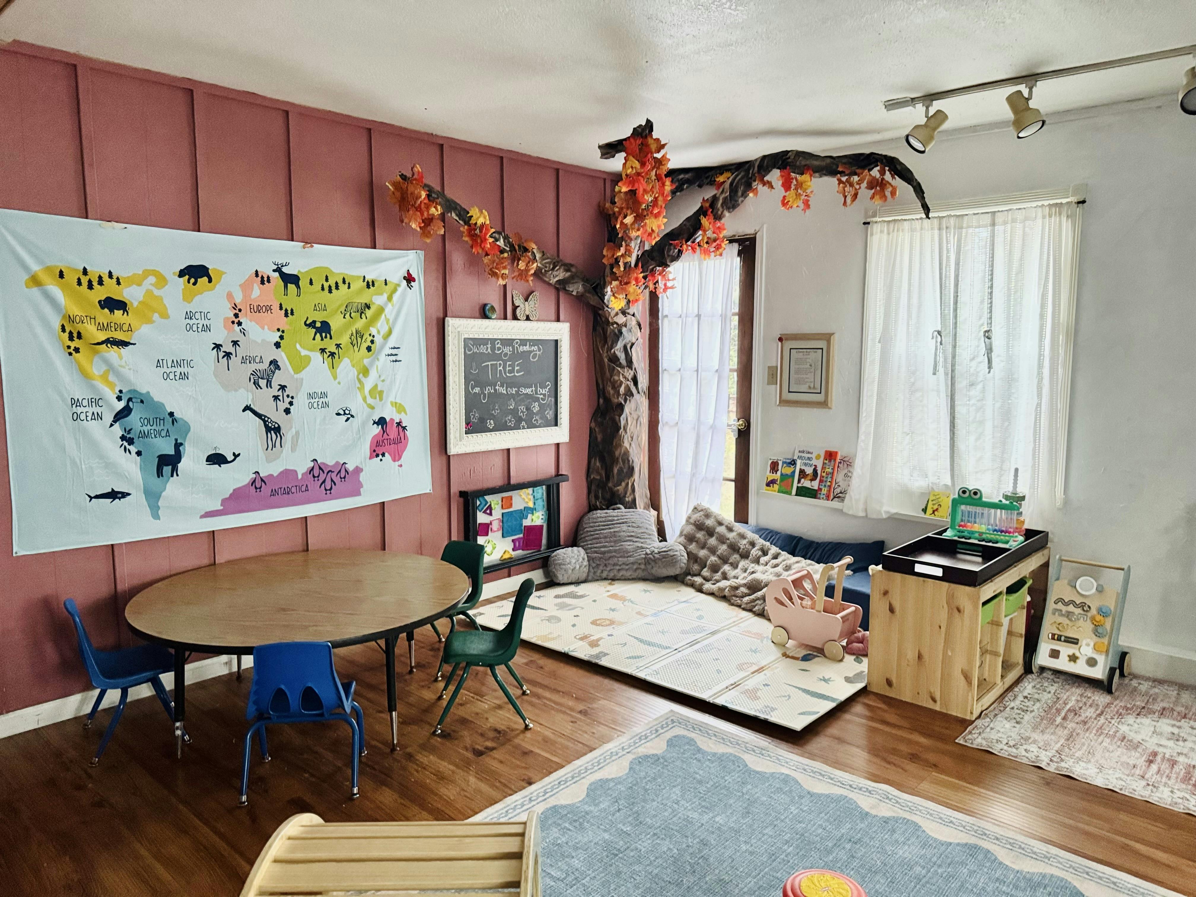 Playroom with a table chairs wall map and a decorative tree in the corner