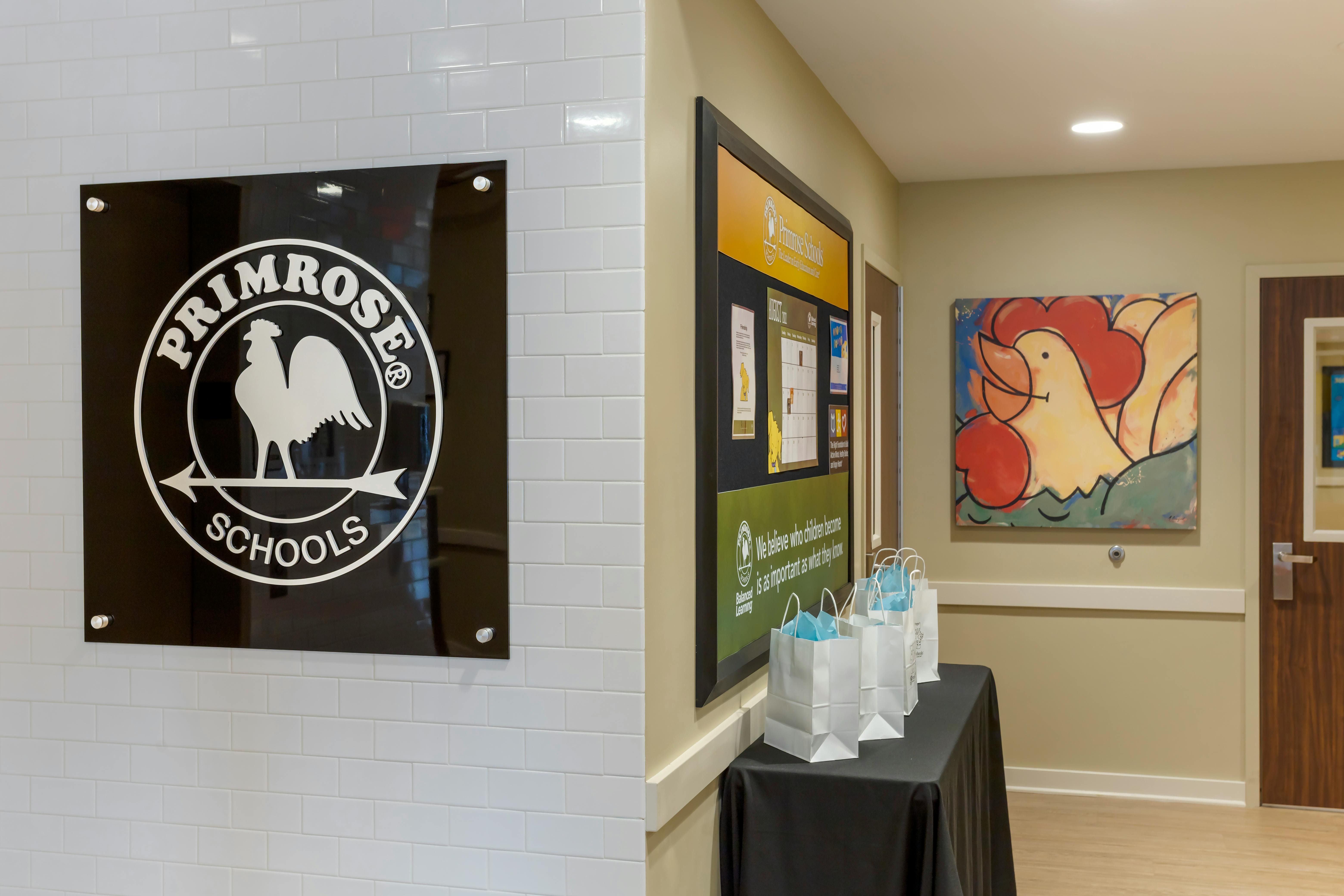 Primrose Schools sign on a white subway tile wall next to an information board