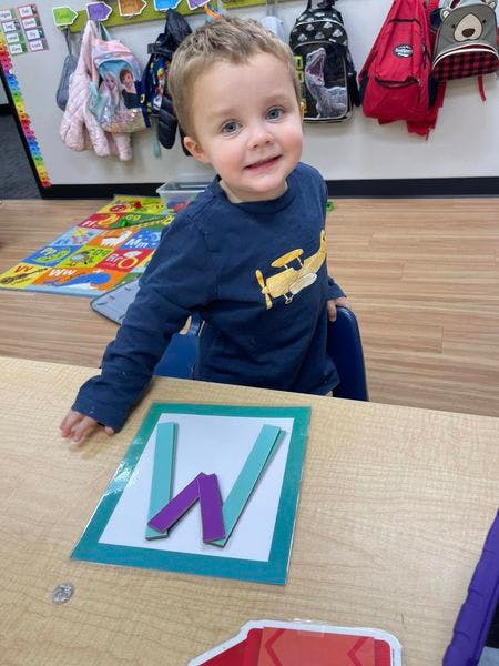 Child at a table with letter W pieces