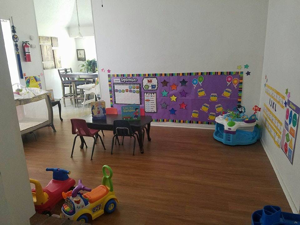 Playroom with small table and chairs, toys on the floor, and bulletin boards