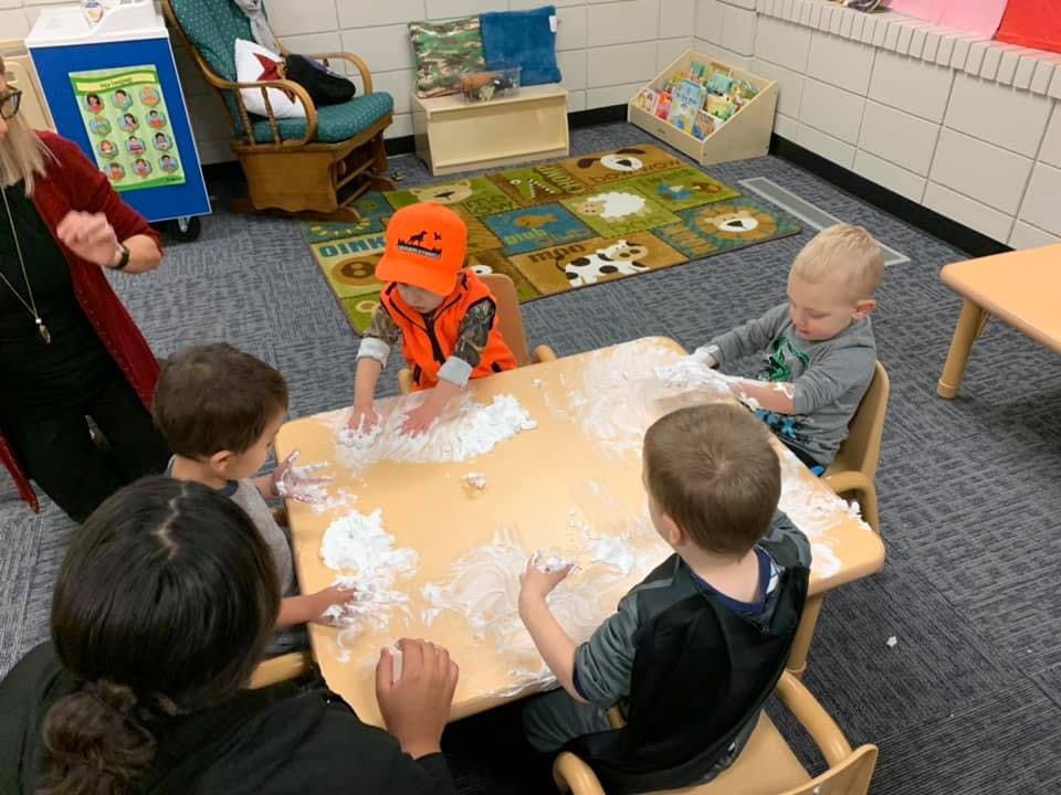Adult and children playing with flour at a table