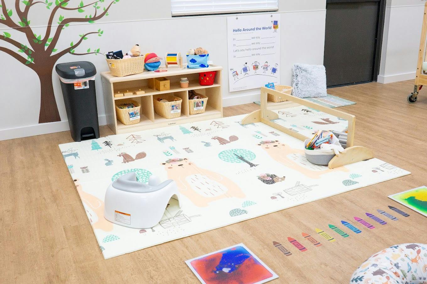 Play area with a mat, low wooden shelving, and child seats in infant seat