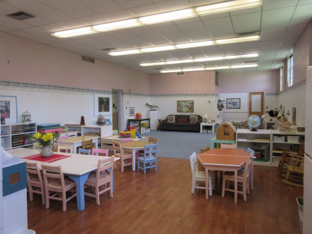 Classroom with small tables and chairs, and a sofa in the background