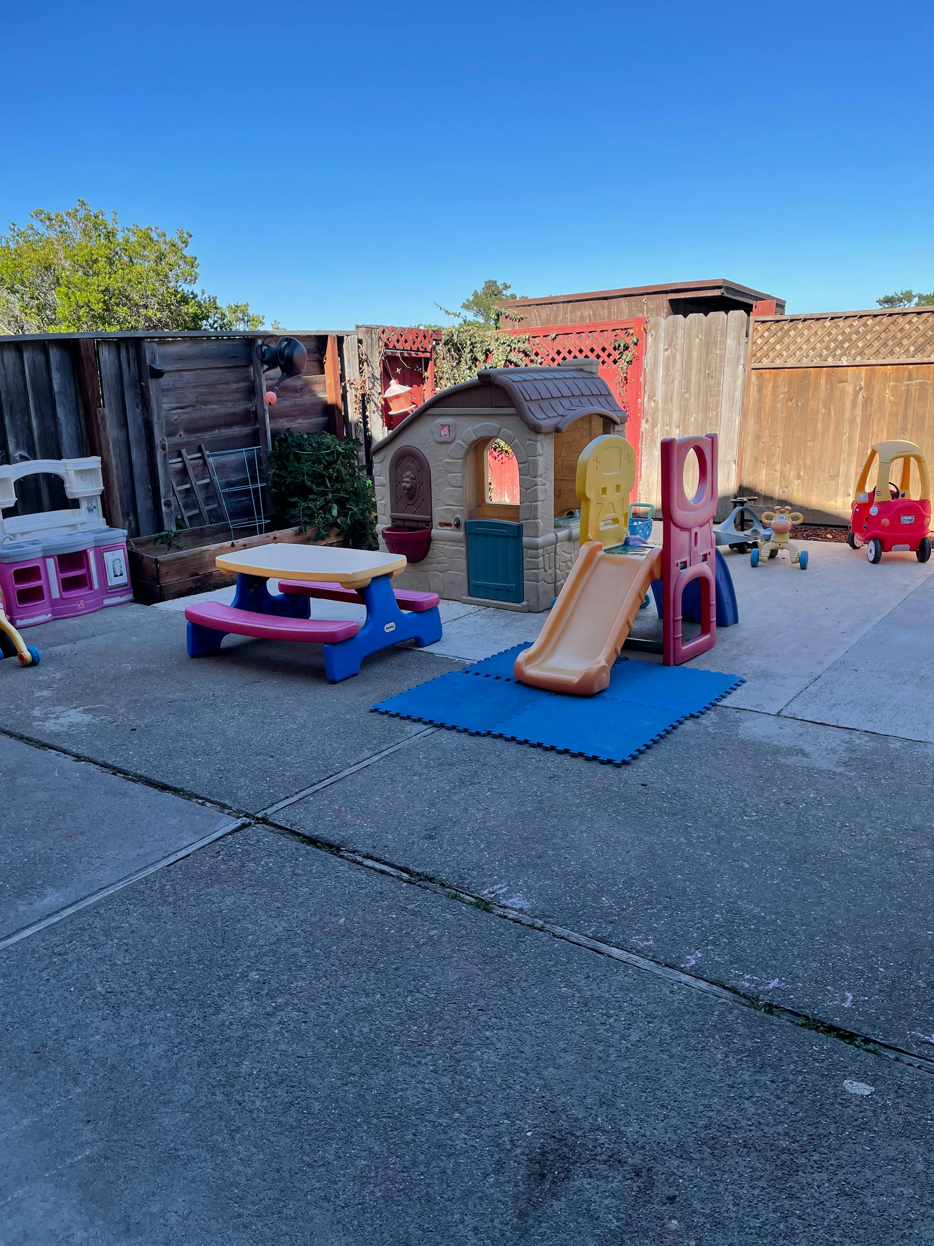 Outdoor play area with a playhouse, slide, and picnic table