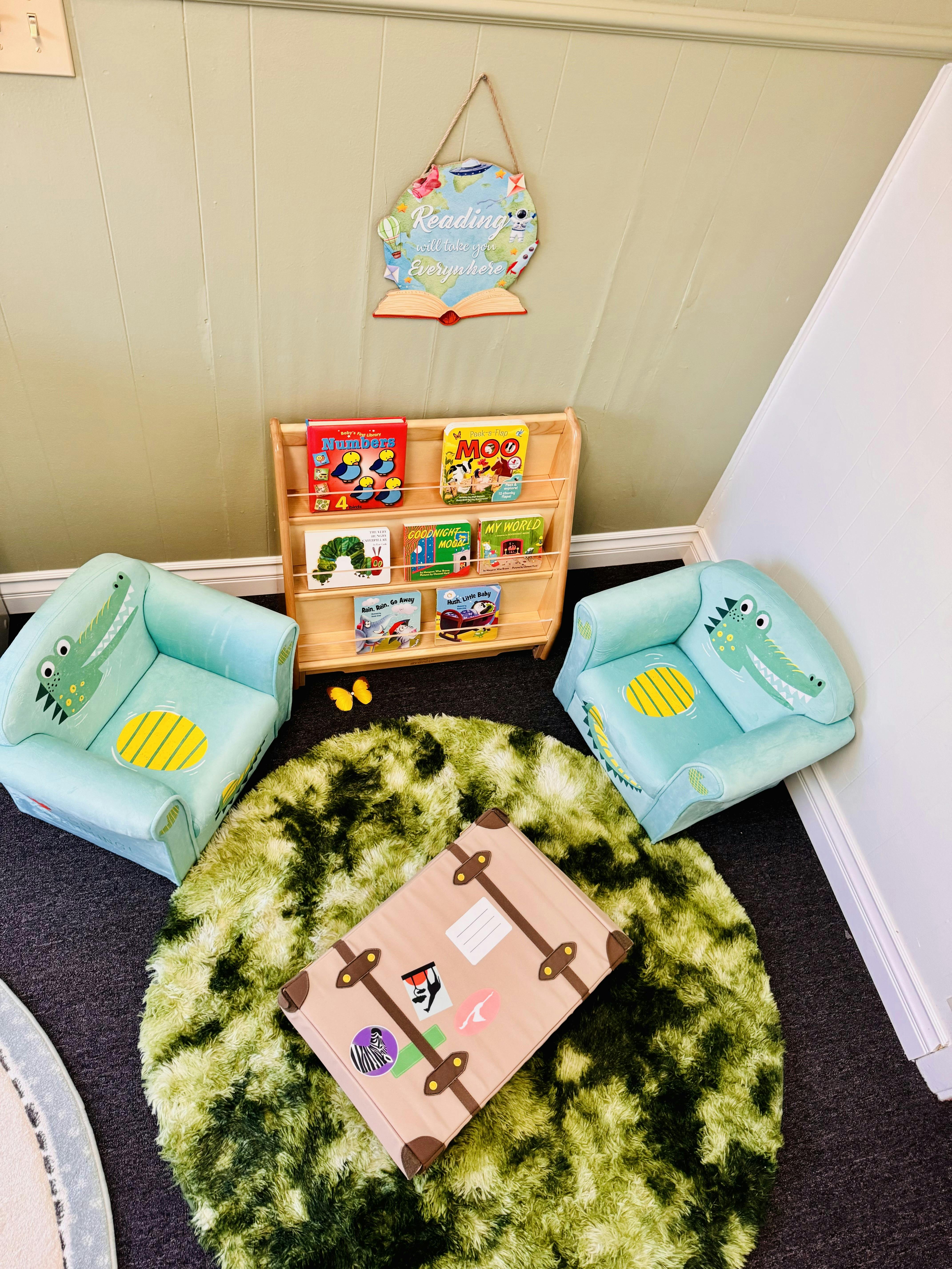 Small wooden bookshelf with children's books flanked by two toy chairs