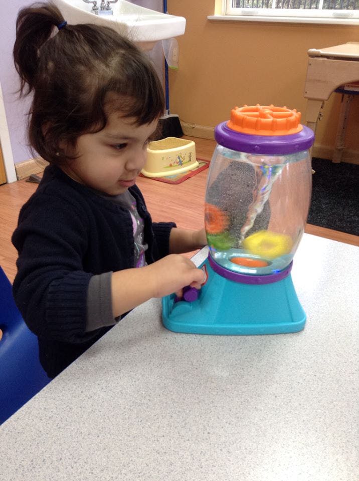 Child playing with a water vortex toy on a table