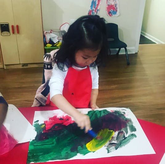 Child painting on paper with a brush