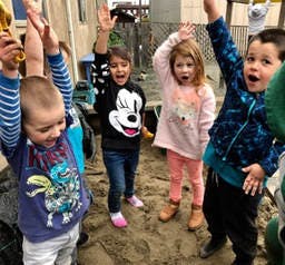 Four children with hands raised