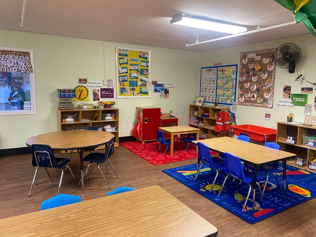 Classroom with child-sized tables and chairs, shelves, and decorations on the walls