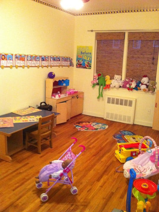 Playroom with a desk, toy kitchen, and various toys on a wooden floor