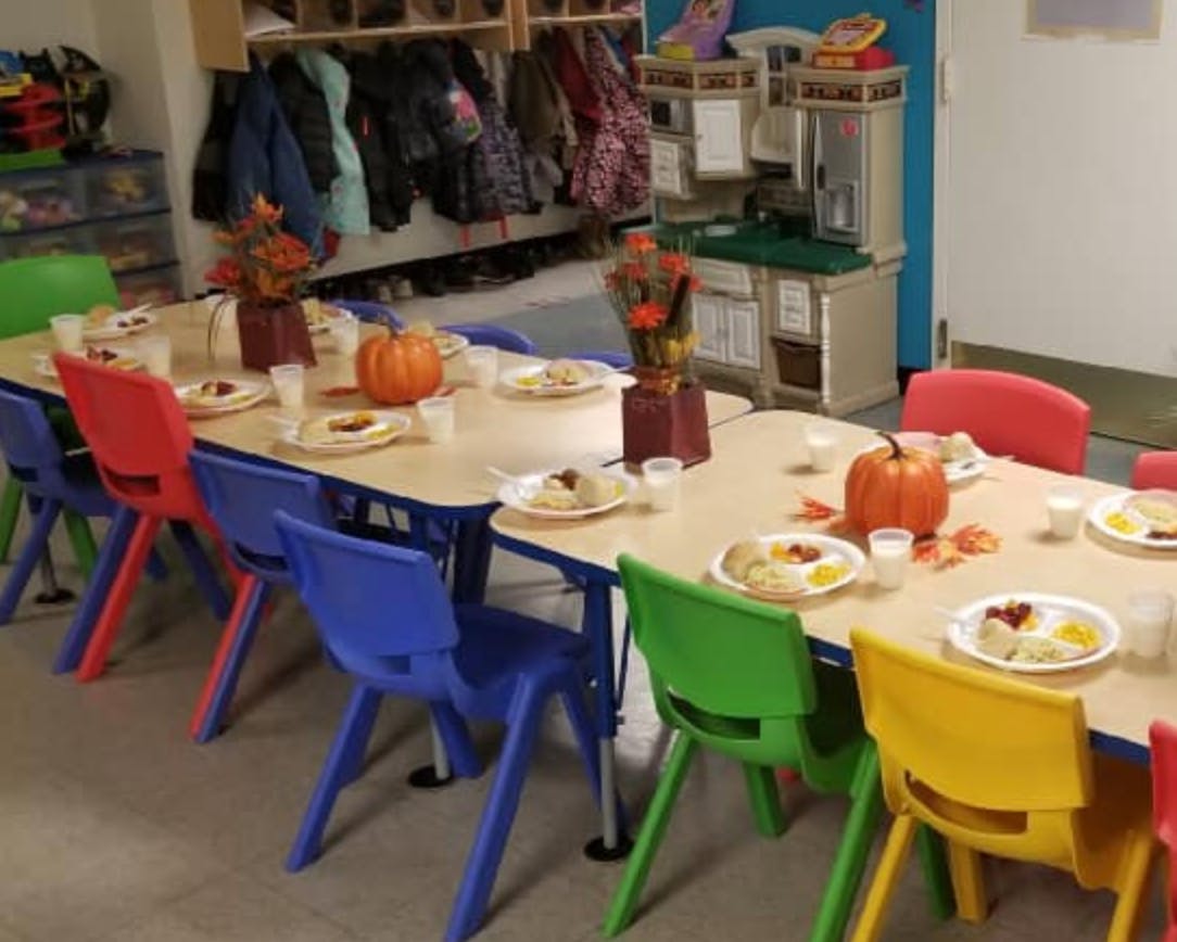 Classroom tables set with plates of food, pumpkins, and colorful chairs