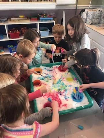 Group of children playing with colorful foam in a sensory bin