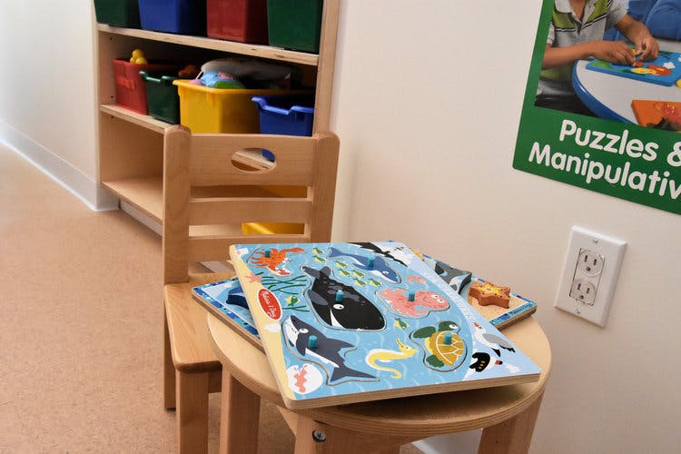 Child's chair and table with a puzzle on top, bookshelf in background